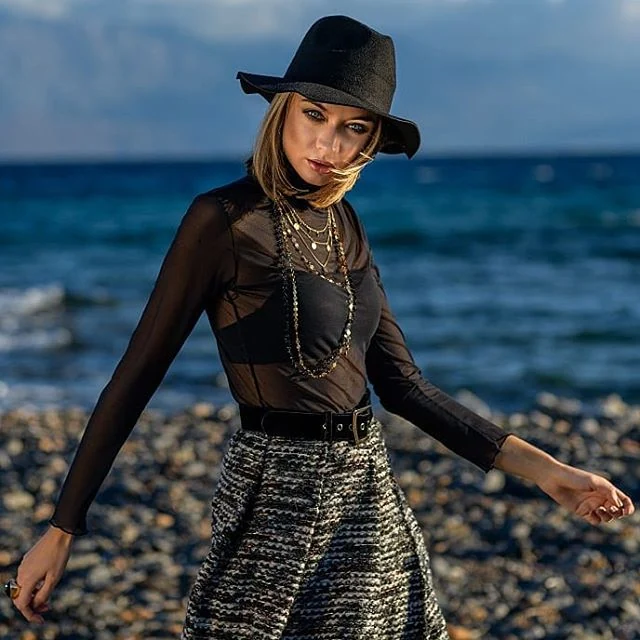 Fashion πορτρέτο γυναίκας με μαύρο καπέλο δίπλα στη θάλασσα